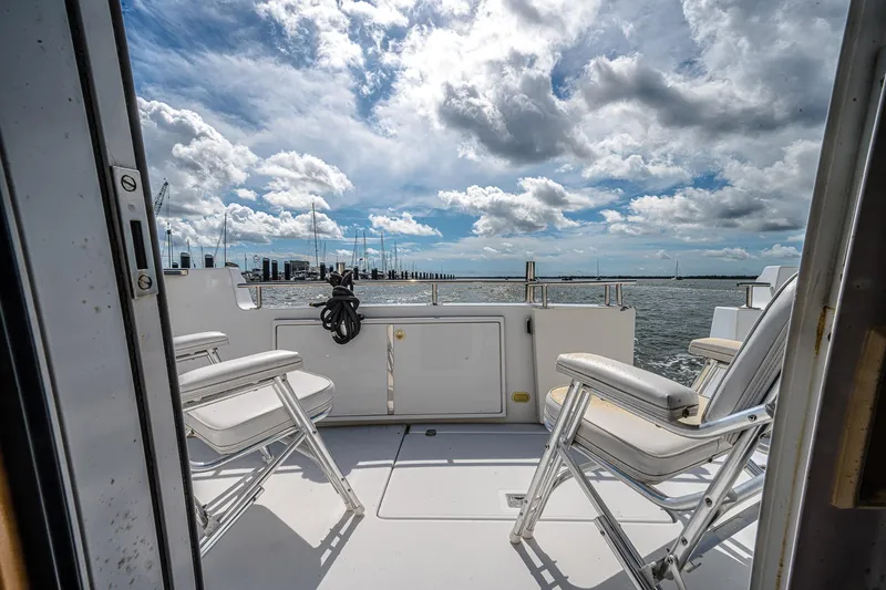 Fiesta Bayb Yacht Photos Pics 2003 Carver 444 Cockpit Motor Yacht deck with chairs, overlooking a scenic waterfront.