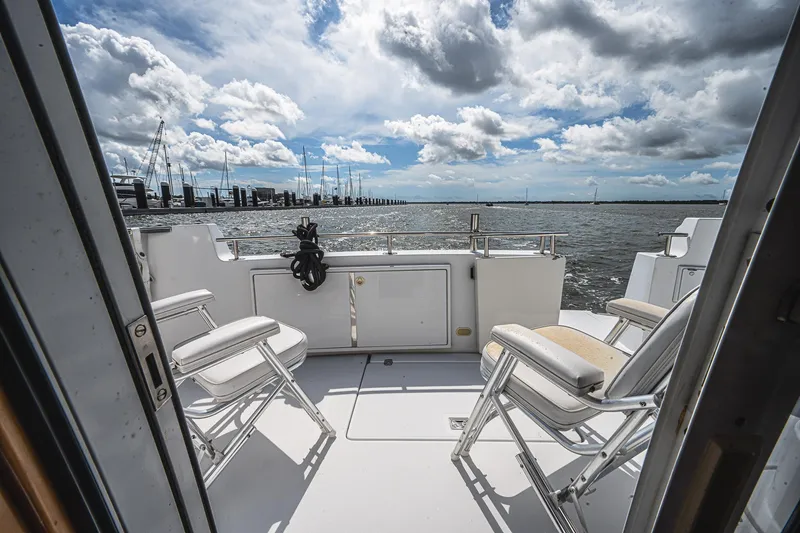 Fiesta Bayb Yacht Photos Pics 2003 Carver 444 Cockpit Motor Yacht deck with chairs, overlooking marina and cloudy sky.
