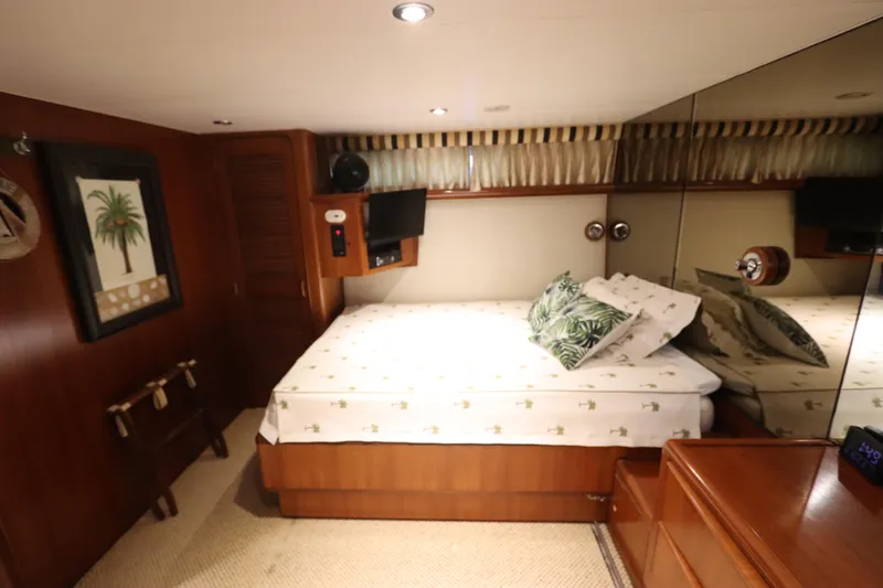  Yacht Photos Pics 1991 Viking Motor Yacht bedroom with wooden decor, bed, and mirrored wall.