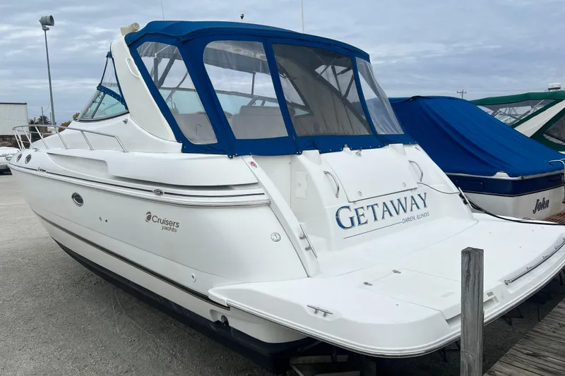 Getaway Yacht Photos Pics 2000 Cruisers Yachts 3870 Express boat with blue canopy, docked outdoors.