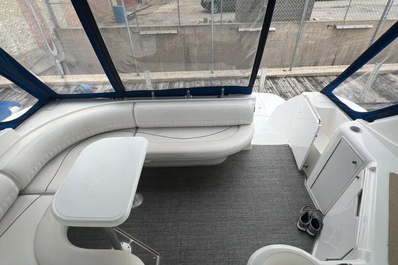 Getaway Yacht Photos Pics 2000 Cruisers Yachts 3870 Express interior with white seating and table, docked by a fence.