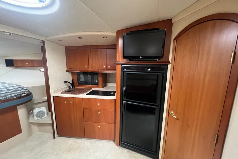 Getaway Yacht Photos Pics 2000 Cruisers Yachts 3870 Express interior with kitchenette, TV, and wood cabinetry.