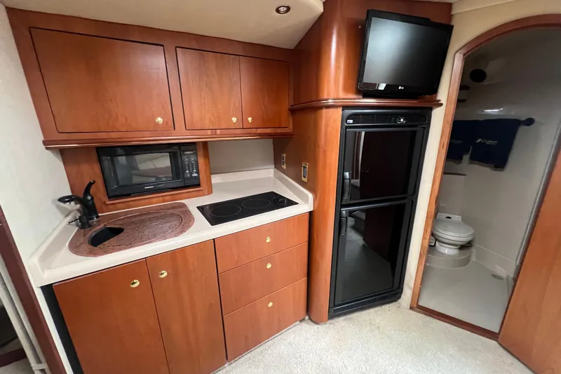 Getaway Yacht Photos Pics 2000 Cruisers Yachts 3870 Express interior kitchen with wood cabinets, microwave, and compact fridge.