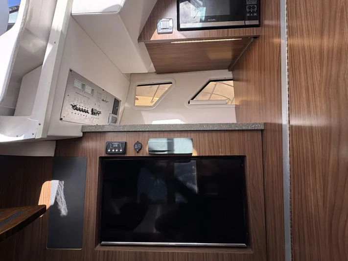 Love You More Yacht Photos Pics Interior of 2019 Four Winns 350H boat with wood paneling, microwave, and control panel.
