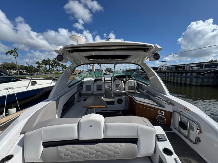 Love You More Yacht Photos Pics 2019 Four Winns 350H boat interior with seating, table, and helm, docked under blue sky.