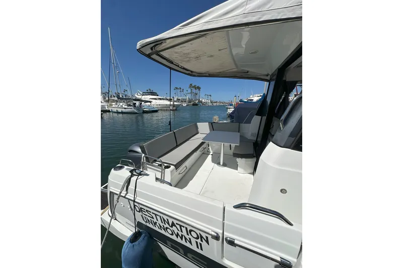 Destination Unknown II Yacht Photos Pics 2021 Jeanneau NC895 boat docked, featuring a spacious rear deck with seating and table.
