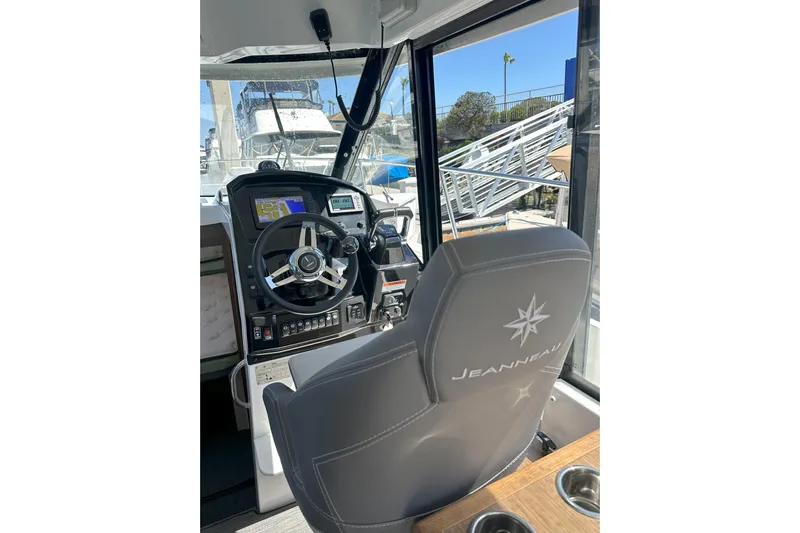 Destination Unknown II Yacht Photos Pics 2021 Jeanneau NC895 helm with steering wheel, navigation display, and branded seat.