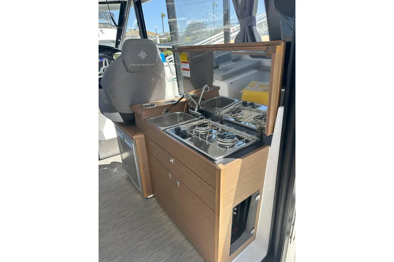 Destination Unknown II Yacht Photos Pics Compact kitchen area in a 2021 Jeanneau NC895 boat, featuring a stove and sink.