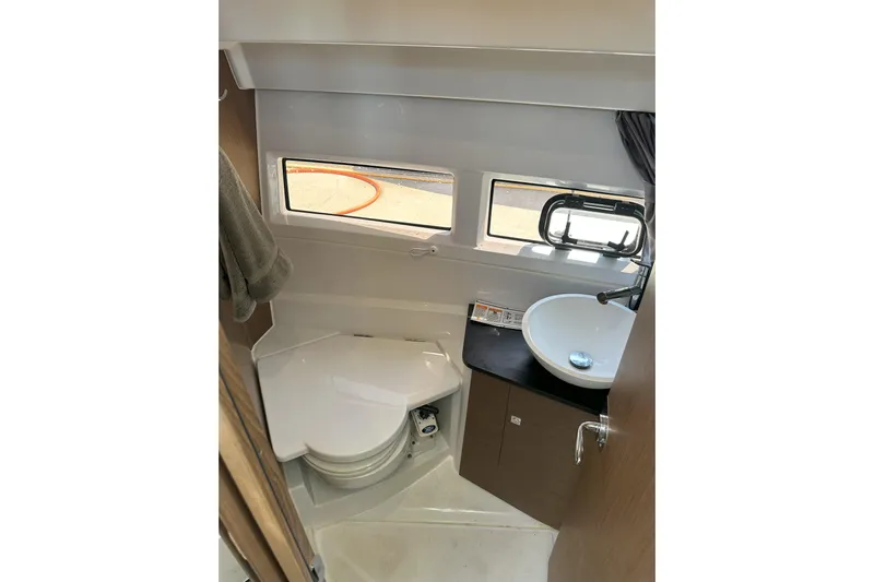 Destination Unknown II Yacht Photos Pics 2021 Jeanneau NC895 boat bathroom with compact toilet, sink, and windows.