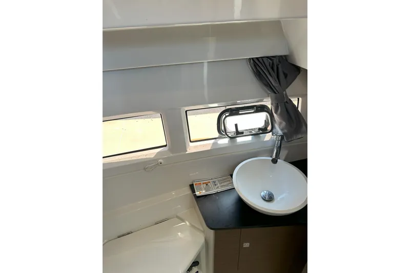 Destination Unknown II Yacht Photos Pics 2021 Jeanneau NC895 bathroom interior with sink, window, and curtain.