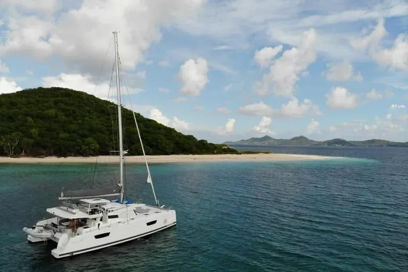 Idalia Yacht Photos Pics 2020 Fountaine Pajot Saona 47 Maestro catamaran anchored near tropical island with lush greenery.