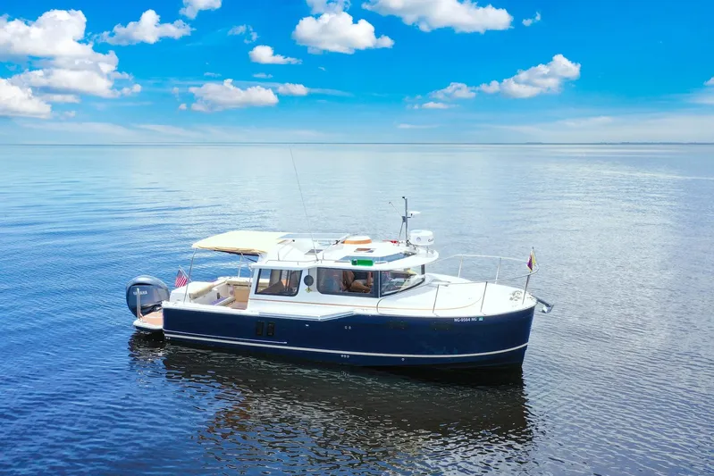  Yacht Photos Pics 2024 Ranger Tugs R-27 boat cruising on calm blue waters under a clear sky.