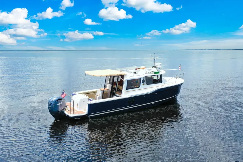  Yacht Photos Pics 2024 Ranger Tugs R-27 boat on calm water under a clear blue sky.
