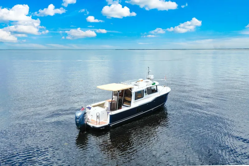  Yacht Photos Pics 2024 Ranger Tugs R-27 boat on calm water under a clear blue sky.