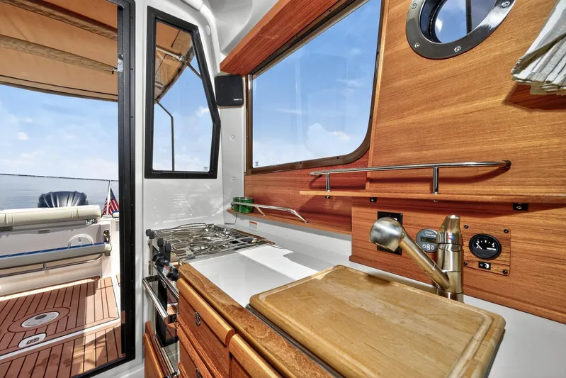  Yacht Photos Pics 2024 Ranger Tugs R-27 interior kitchen with wooden cabinetry and ocean view.