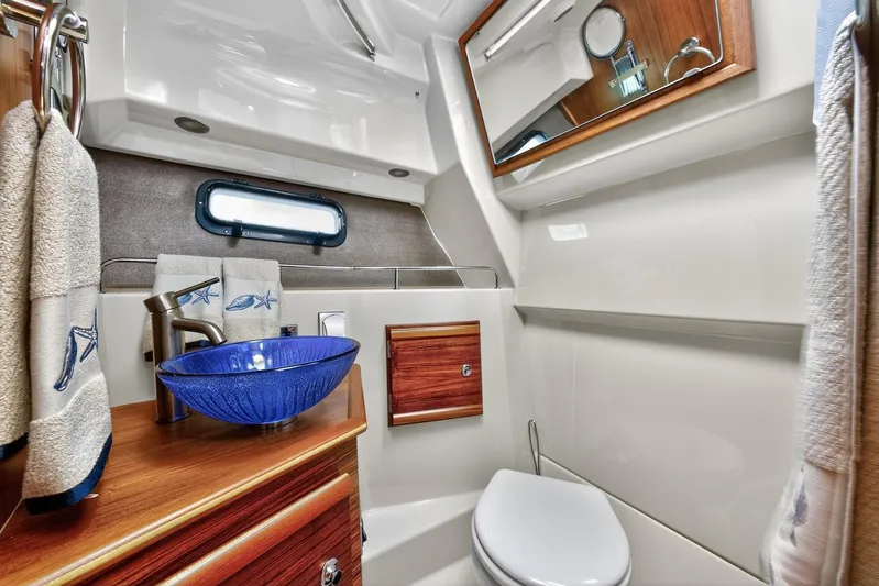  Yacht Photos Pics 2024 Ranger Tugs R-27 bathroom with blue glass sink and wooden accents.