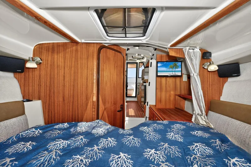  Yacht Photos Pics 2024 Ranger Tugs R-27 interior cabin with wood paneling, bed, and TV.