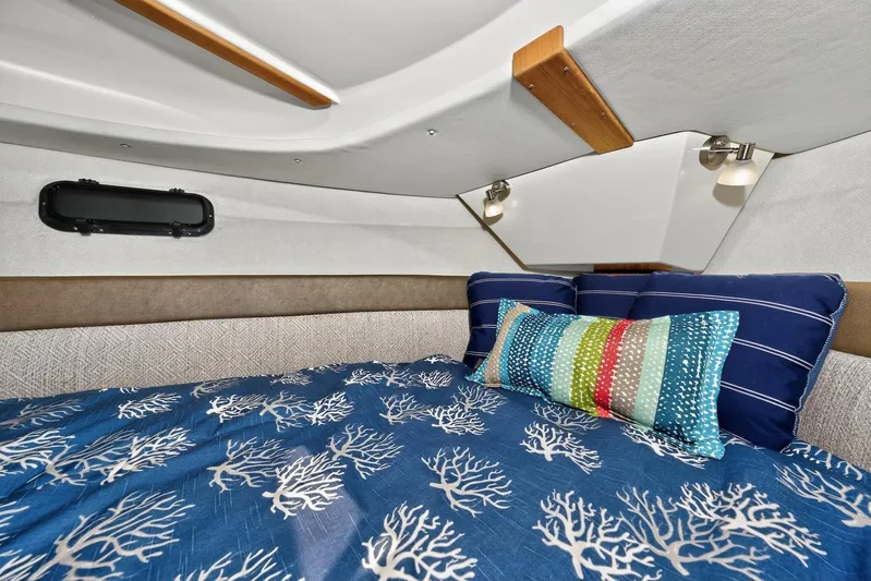  Yacht Photos Pics 2024 Ranger Tugs R-27 cabin interior with nautical-themed bedding and colorful pillows.