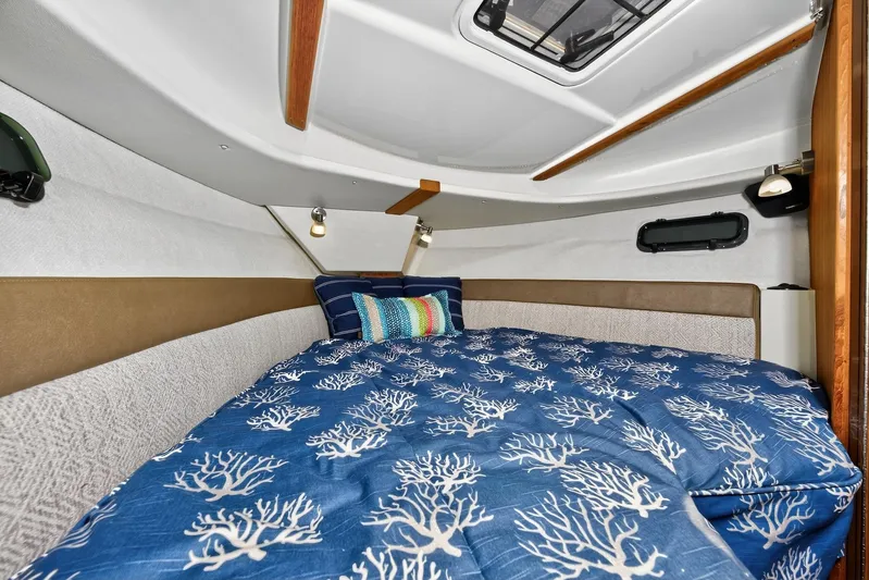  Yacht Photos Pics 2024 Ranger Tugs R-27 cabin interior with cozy bed and nautical-themed bedding.