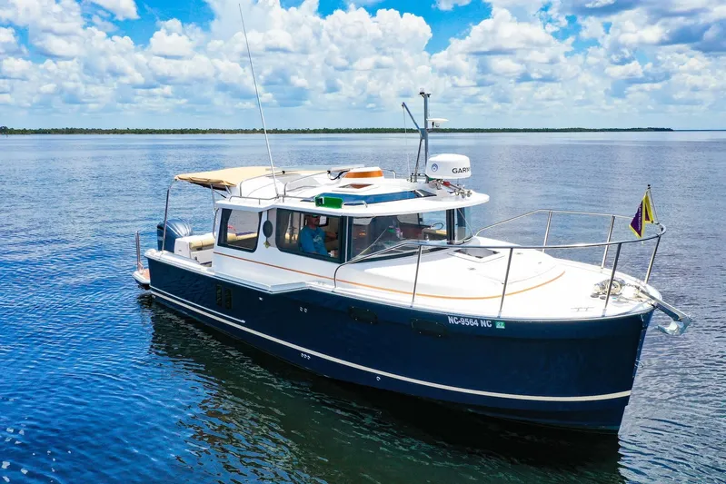  Yacht Photos Pics 2024 Ranger Tugs R-27 boat cruising on calm water under a partly cloudy sky.
