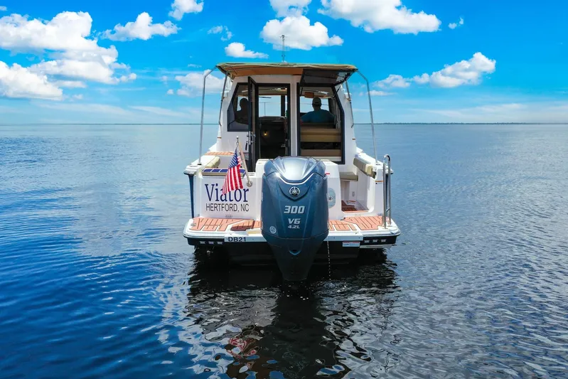  Yacht Photos Pics 2024 Ranger Tugs R-27 boat on calm water, rear view with outboard motor.