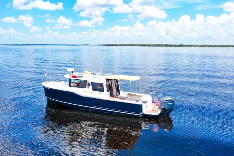  Yacht Photos Pics 2024 Ranger Tugs R-27 boat cruising on a calm, blue lake under a clear sky.