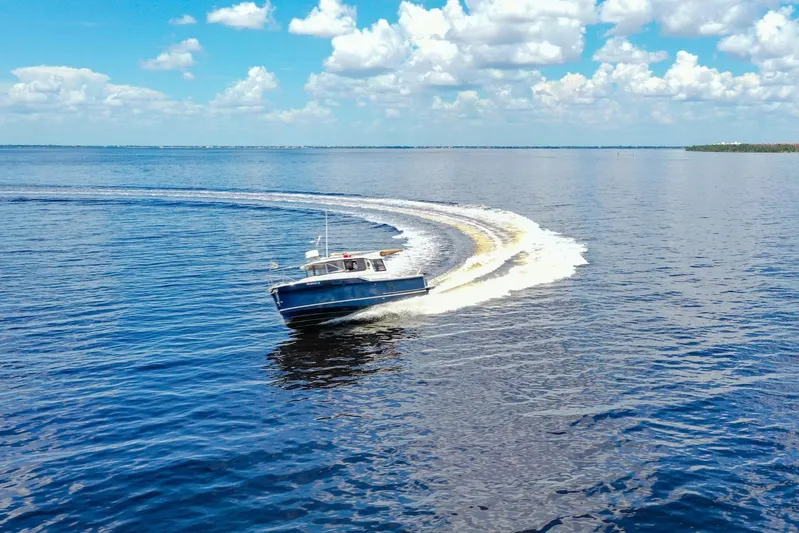  Yacht Photos Pics 2024 Ranger Tugs R-27 cruising on open water under a bright blue sky.