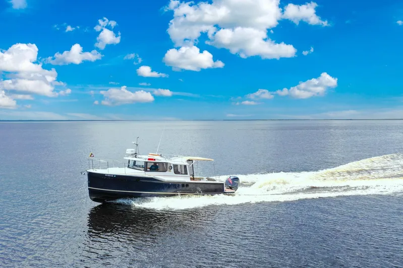  Yacht Photos Pics 2024 Ranger Tugs R-27 cruising on open water under a clear blue sky.