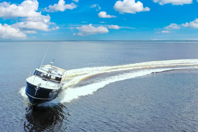  Yacht Photos Pics 2024 Ranger Tugs R-27 cruising on open water under a clear blue sky.