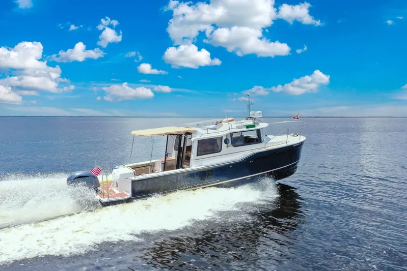  Yacht Photos Pics 2024 Ranger Tugs R-27 cruising on open water under a clear blue sky.