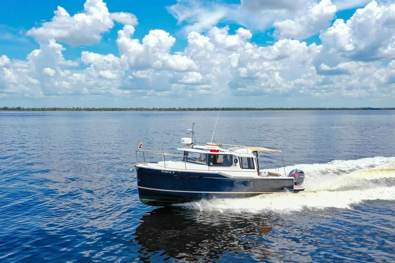  Yacht Photos Pics 2024 Ranger Tugs R-27 cruising on a serene lake under a vibrant blue sky.