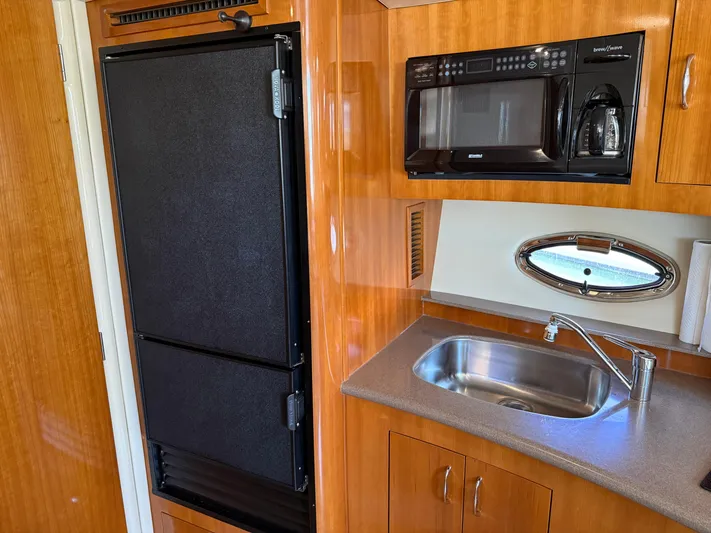  Yacht Photos Pics 2006 Carver 36 Mariner kitchen with fridge, microwave, sink, and wooden cabinetry.