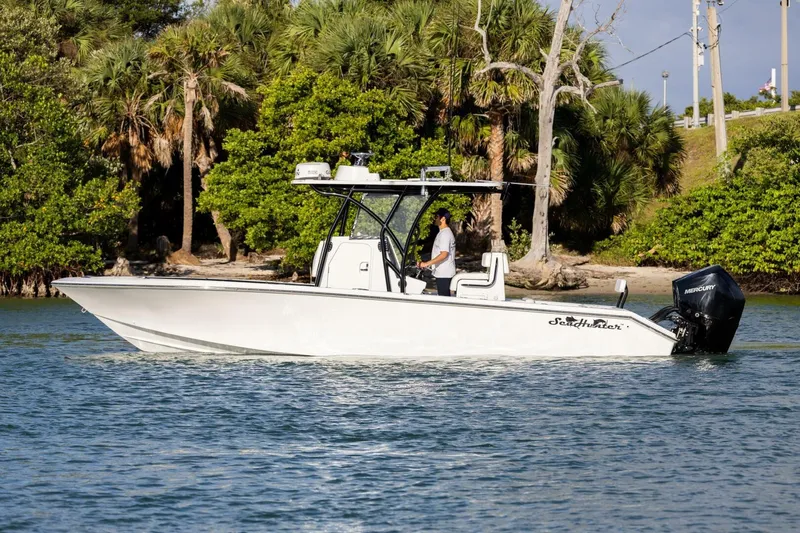  Yacht Photos Pics 2019 SeaHunter 28 Floridian boat cruising on water near lush greenery.