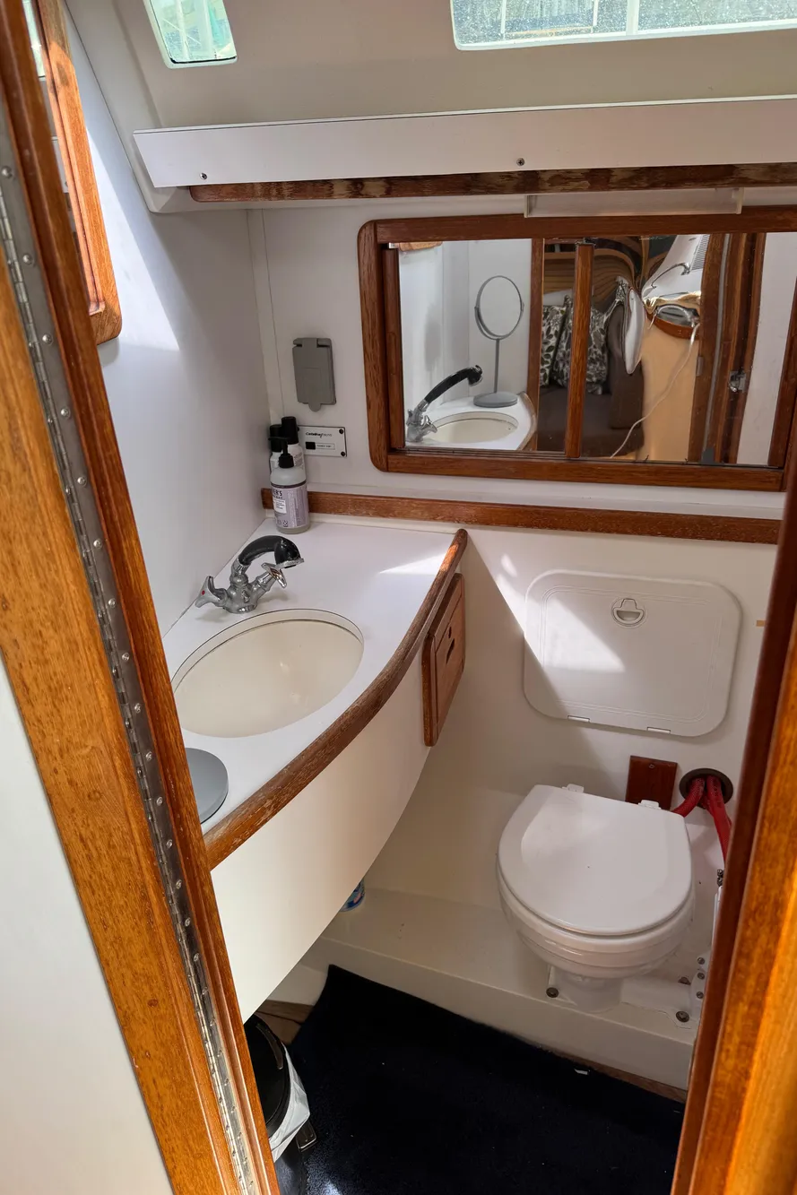 1993 Catalina 42 yacht bathroom with sink, mirror, and toilet, featuring wood accents.