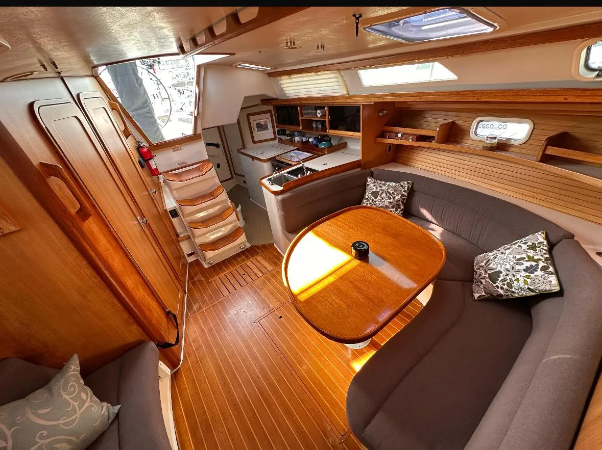 Cozy interior of a 1993 Catalina 42 sailboat with wooden furnishings and a dining area.