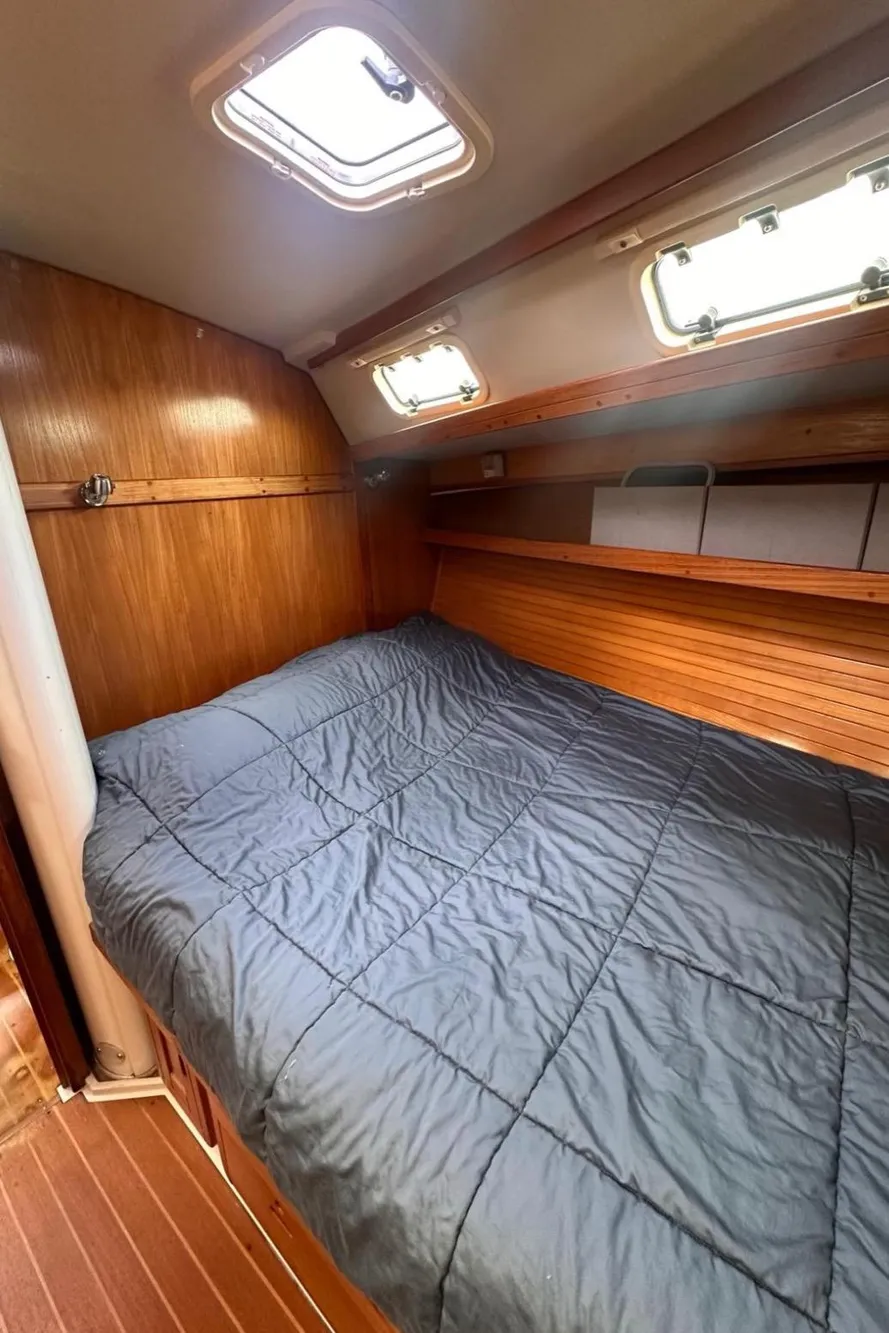 Cozy cabin interior of 1993 Catalina 42 sailboat with wooden finish and comfortable bedding.