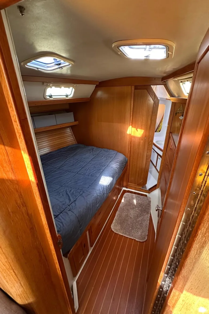 Cozy cabin interior of a 1993 Catalina 42 sailboat with wooden finishes and a comfortable bed.