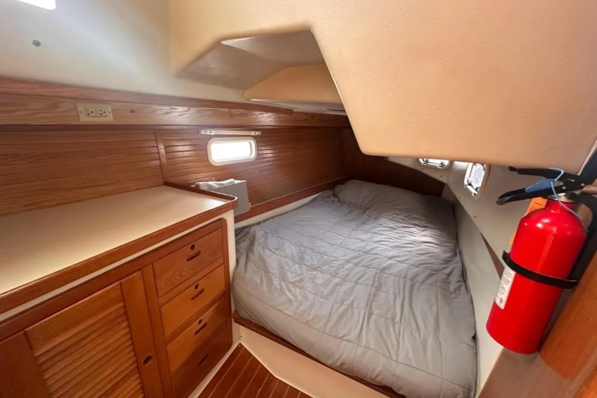 Cozy cabin interior of 1993 Catalina 42 sailboat with bed and wooden cabinetry.