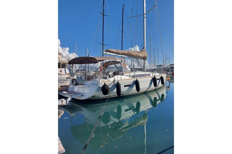 Fiesta Yacht Photos Pics 2019 Jeanneau Sun Odyssey 519 sailboat docked in marina, reflecting on calm water.
