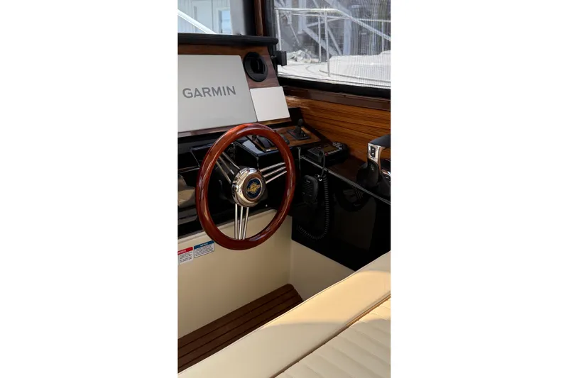  Yacht Photos Pics 2026 Ranger Tugs R-27 helm with Garmin navigation, wooden steering wheel, and modern controls.