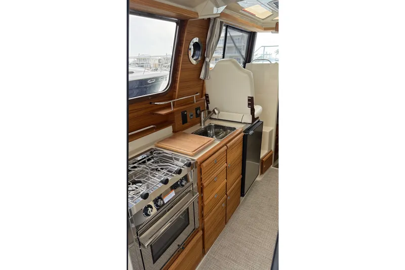  Yacht Photos Pics Interior of 2026 Ranger Tugs R-27, featuring a compact kitchen with stove and sink.
