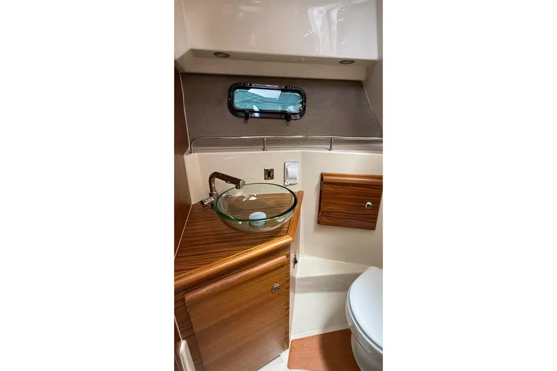  Yacht Photos Pics 2026 Ranger Tugs R-27 boat bathroom with glass sink and wooden cabinetry.