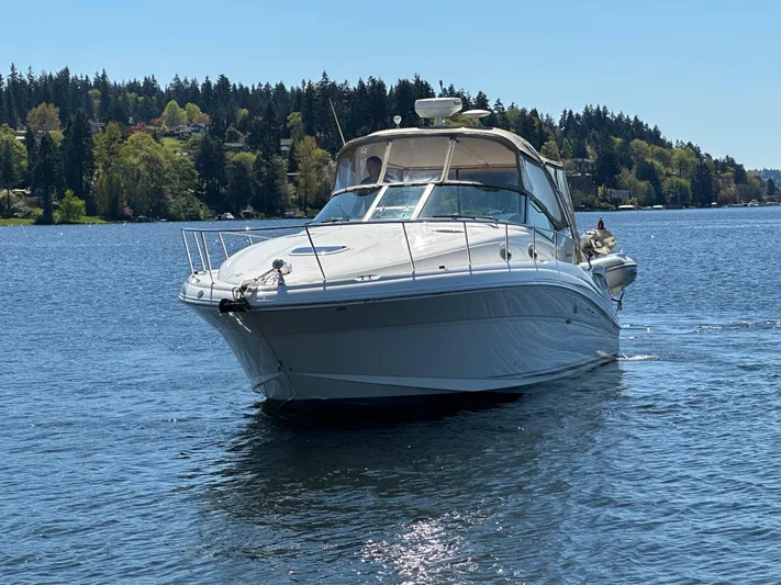  Yacht Photos Pics 2004 Sea Ray 340 Sundancer cruising on a serene lake with forested shoreline.