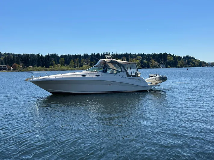  Yacht Photos Pics 2004 Sea Ray 340 Sundancer cruising on a serene lake under a clear blue sky.