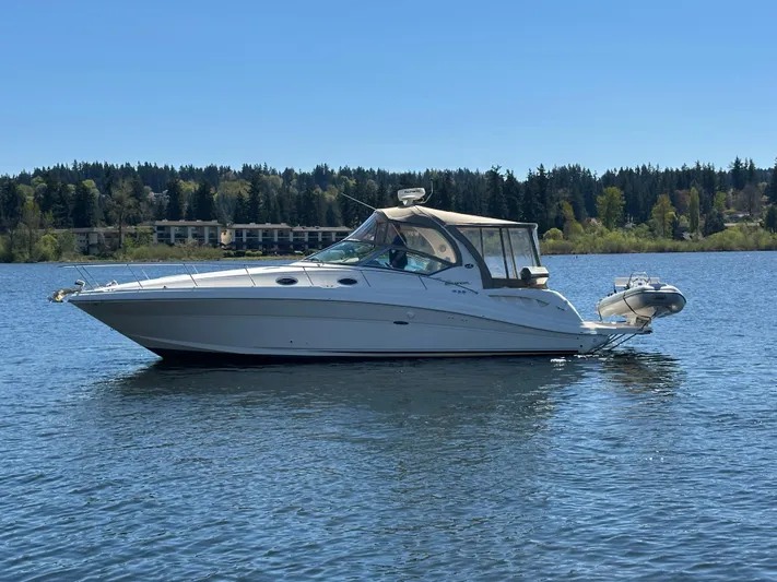  Yacht Photos Pics 2004 Sea Ray 340 Sundancer boat on a calm lake with forested shoreline.