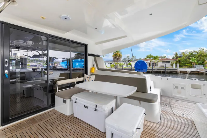 Benedetto Yacht Photos Pics Spacious deck of 2020 Lagoon 42 catamaran with seating and table, docked by waterfront.