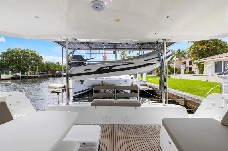 Benedetto Yacht Photos Pics 2020 Lagoon 42 yacht deck with dinghy, docked by waterfront homes.