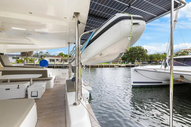 Benedetto Yacht Photos Pics 2020 Lagoon 42 catamaran with solar panels and dinghy, docked in a marina.