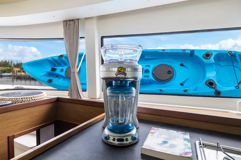 Benedetto Yacht Photos Pics Blender and book on Lagoon 42 yacht with blue kayak outside window.