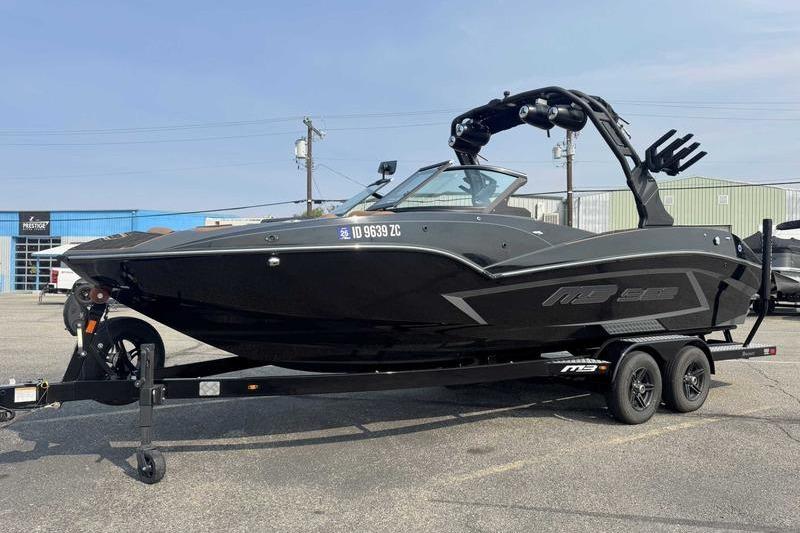 2024 MB Alpha 23 boat on trailer, sleek black design, parked outdoors.